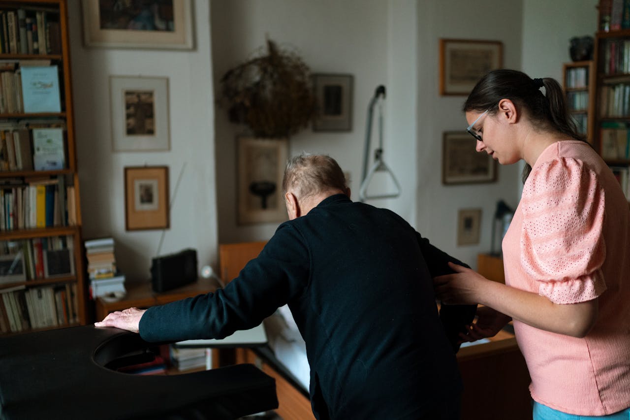 Young caregiver assisting senior man in a stylish Prague living room.